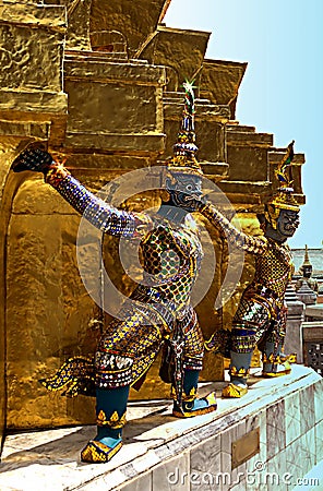 Colorful demon statues surrounding the base of a chedi. Stock Photo