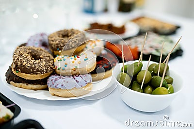 Colorful donuts with icing and green olives on the table Stock Photo