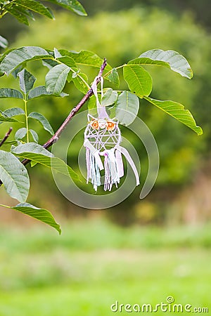 Colorful dreamcatcher outdoors on summer nature background. Handmade decor made of feathers, ribbons, threads and beads. Stock Photo