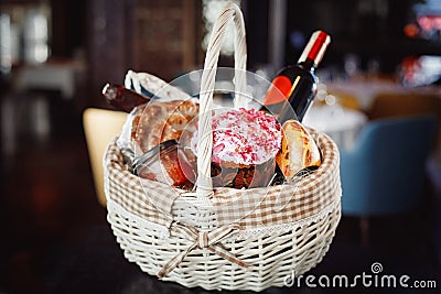 Colorful easter in a basket with, red wine, jamon or jerky and dry smoked sausage on a wooden table Stock Photo