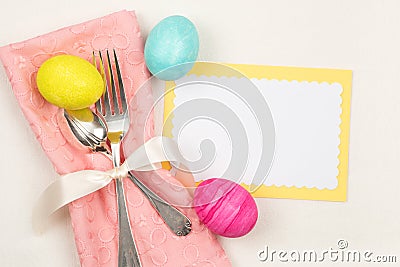 Colorful Easter Egg Table Setting with Silverware, Dyed eggs, Pink Napkin, Card on off white cloth Stock Photo