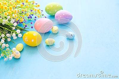 Colorful easter eggs and branch with flowers on blue wooden desk Stock Photo