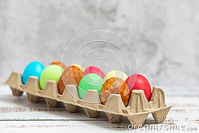 Colorful Easter eggs in a cardboard egg box on light background Stock Photo