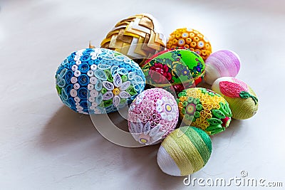 Colorful Easter eggs with floral ornaments, origami decorations and crewel wool against white background Stock Photo