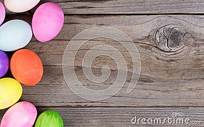 Colorful eggs for Easter holiday forming left hand border on rustic wood Stock Photo