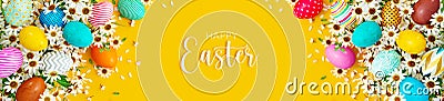 Colorful eggs with white spring flowers and Happy Easter text on yellow background Stock Photo