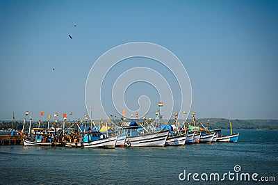 Colorful fishing boats with blue and white hulls and Indian flags on the masts, on the fishing pier in Goa. Wooden boats Stock Photo