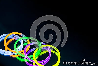 Colorful fluorescent light neon glow stick bracelet strap wristband on mirror reflection black background Stock Photo