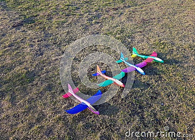 Colorful foam toy airplanes lie in a row on the grass. Stock Photo