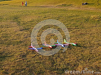 Colorful foam toy airplanes lie in a row on the grass. Stock Photo