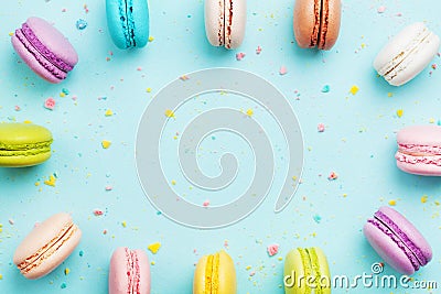 Colorful frame from cake macaron or macaroon on mint pastel background from above. French cookies on dessert top view. Stock Photo