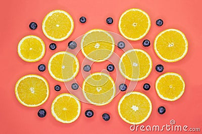 Colorful fruit pattern of fresh orange slices and blueberries on coral background Stock Photo