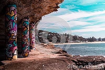 Graffiti art on pillars supporting the rocks at South Palm Beach on a sunny day Editorial Stock Photo