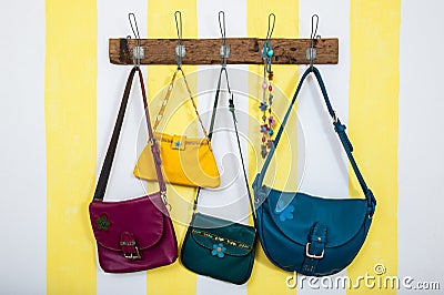 Colorful leather bags hanging on wooden wardrobe Stock Photo