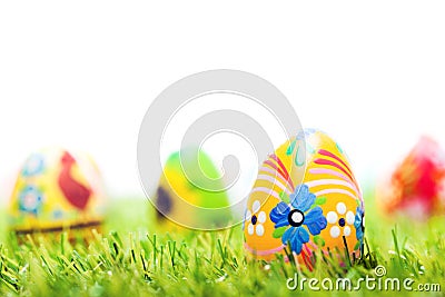Colorful hand painted Easter eggs in grass. Spring theme, white copy-space Stock Photo