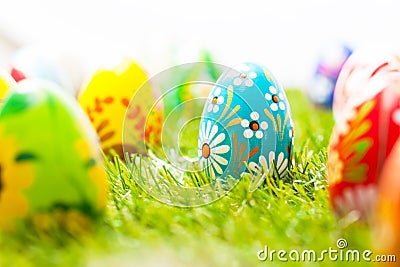 Colorful hand painted Easter eggs in grass. Spring theme, white copy-space Stock Photo