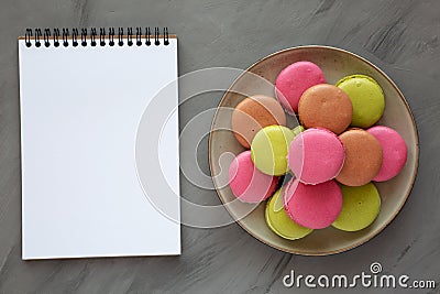 Colorful Homemade French Macarons on a Plate, blank notepad, top view. Flat lay, overhead, from above Stock Photo
