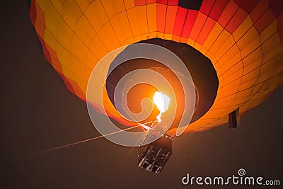 Colorful hot air balloon flying with flames against dark sky at night Stock Photo