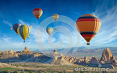 Colorful hot air balloons fly in blue sky over amazing valleys with fairy chimneys in Cappadocia, Turkey Stock Photo