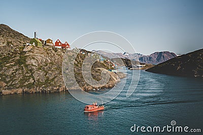 Colorful houses dot the hillsides of the fishing town of Kangaamiut, West Greenland. Icebergs from Kangia glacier in Editorial Stock Photo