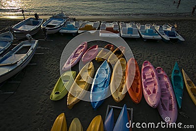 Colorful kayaks and boats on the beach at sunset. Editorial Stock Photo