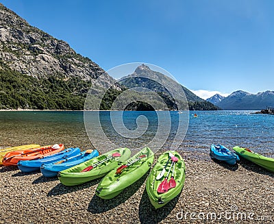 Colorful Kayaks in a lake surrounded by mountains at Bahia Lopez in Circuito Chico - Bariloche, Patagonia, Argentina Stock Photo