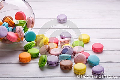 Colorful macaroons or macarons are poured out of the crystal vase on a white background. French sweets Stock Photo