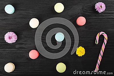 Colorful macaroons on wooden table. Sweet macarons, flowers and lollipop. Top view with copy space for your text Stock Photo