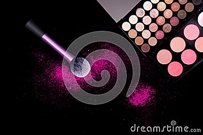 Colorful makeup palette and pink big brush to apply powder on pure black background. Professional makeup equipment. Stock Photo