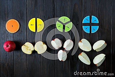 Colorful math fractions and apples as a sample on brown wooden background or table. interesting math for kids. Education Stock Photo