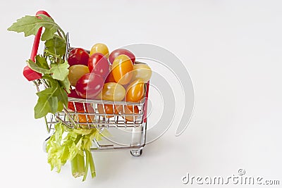 Colorful multicolored ripe cherries tomatoes in miniature toy, trolley closeup, light background, copy space. Concept of Stock Photo
