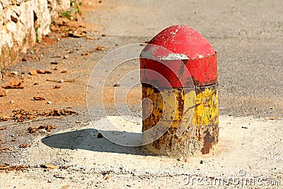 Colorful old dilapidated partially rusted concrete and metal parking security barrier or bollard mounted on asphalt to prevent Stock Photo