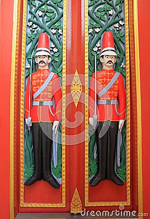Colorful old style wooden door depicting, carved soldiers as Guardians on double doors at the entrance to an old temple Stock Photo