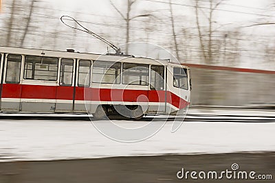 Colorful orange fast moving tram in blurred street with snow Stock Photo