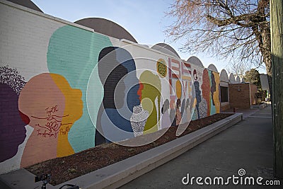 a colorful orange, yellow, blue and pink wall mural with silhouettes of people and the words Be Love at the King Center in Atlanta Editorial Stock Photo