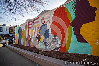 a colorful orange, yellow, blue and pink wall mural with silhouettes of people and the words Be Love at the King Center in Atlanta Editorial Stock Photo