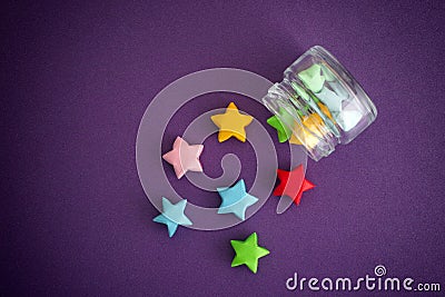 Colorful origami lucky stars spilling out of a jar Stock Photo