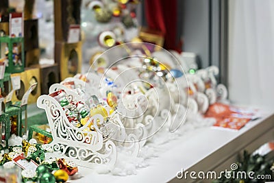 Colorful ornaments, Christmas balls and white wooden sledges. Sale of Christmas decorations. Abstract light blurred Stock Photo