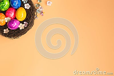 Colorful painted Easter Egg Nest with orange pastel colored background top view, Happy Easter Holliday concept background with Stock Photo