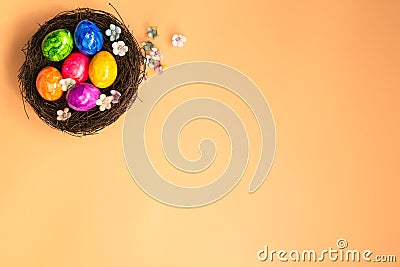 Colorful painted Easter Egg Nest with orange pastel colored background top view, Happy Easter Holliday concept background with Stock Photo