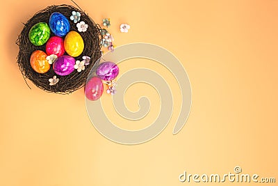 Colorful painted Easter Egg Nest with orange pastel colored background top view, Happy Easter Holliday concept background with Stock Photo