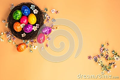 Colorful painted Easter Egg Nest with orange pastel colored background top view, Happy Easter Holliday concept background with Stock Photo