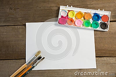 Colorful palette paintbrushes and blank paper on wooden surface Stock Photo