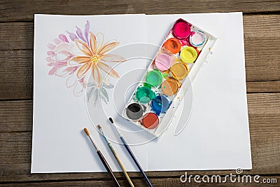 Colorful palette, paintbrushes and paper on wooden surface Stock Photo