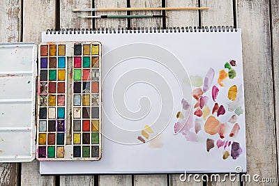 Colorful palette, paintbrushes and paper on wooden surface Stock Photo