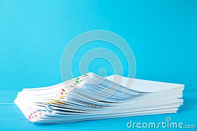 Colorful paper clip with pile of overload white paperwork on blue Stock Photo