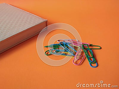 Colorful paper clips isolated on orange background Stock Photo