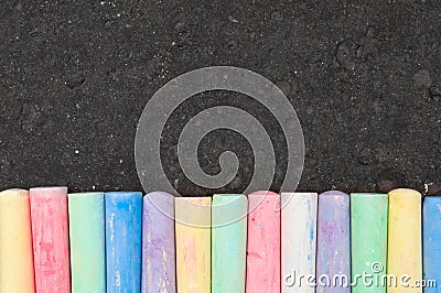 Colorful pastel sidewalk chalk on dark asphalt background. Stock Photo