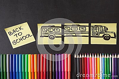 Colorful pencils, titles Back to school and school bus drawn on the pieces of paper on the chalkboard Stock Photo