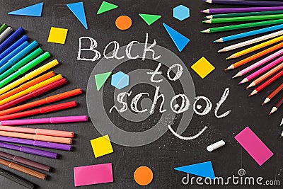 Colorful pens, pencils, title Back to school written by chalk and geometric figures on the chalkboard Stock Photo